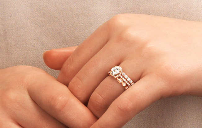 Close up of woman's hands as she wears a gold and diamond engagement ring.