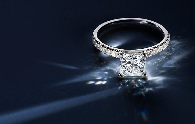 Princess cut diamond solitaire engagement ring on a blue background