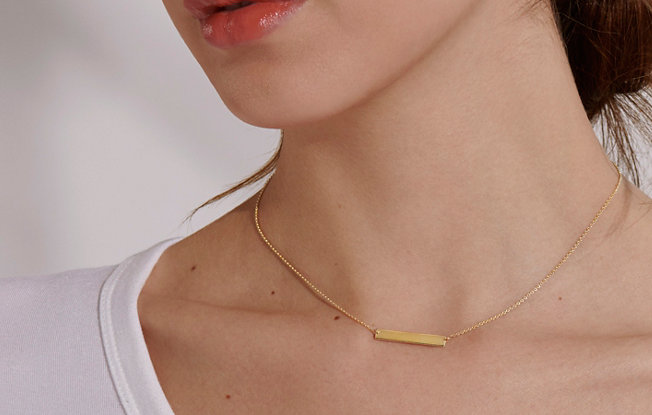 A woman wearing an engravable bar necklace