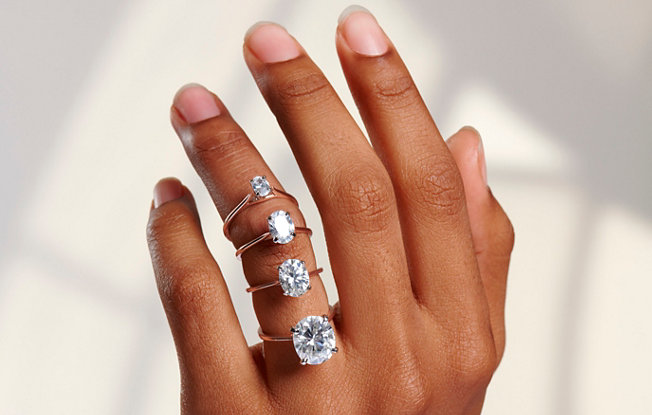 4 oval cut diamond engagement rings of varying size displayed on a feminine hand