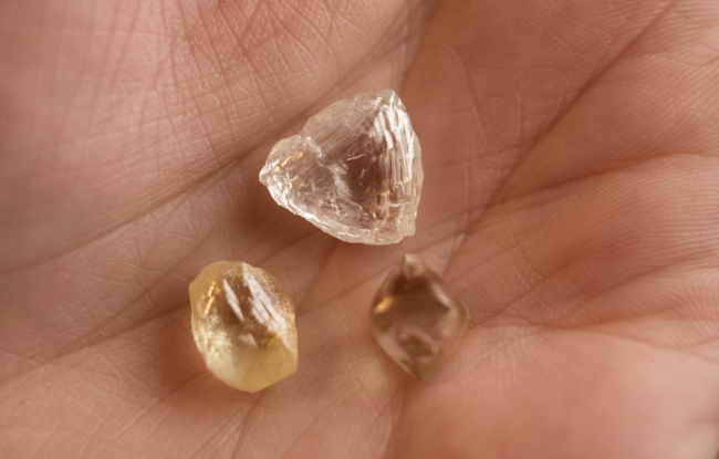Collection of rough diamonds in the palm of a person's hand