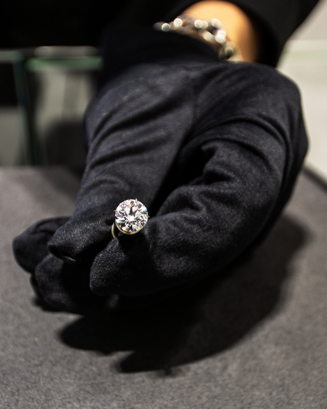 A 2.2 carat diamond is displayed in a gloved hand.