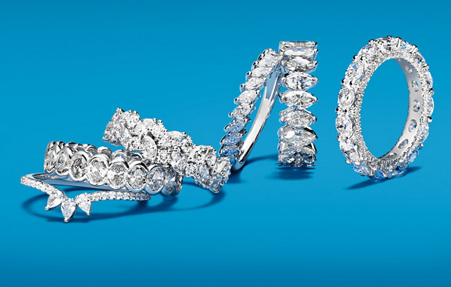 6 Blue Nile diamond wedding rings set in platinum on a blue background