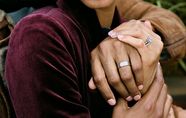 Couple holding hands with their wedding rings on.