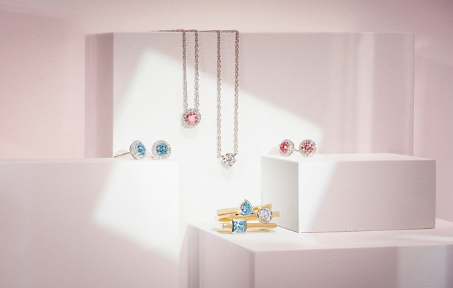 Diamond earrings, pendants, and rings made from lightbox lab grown white and colored diamonds on a pink background