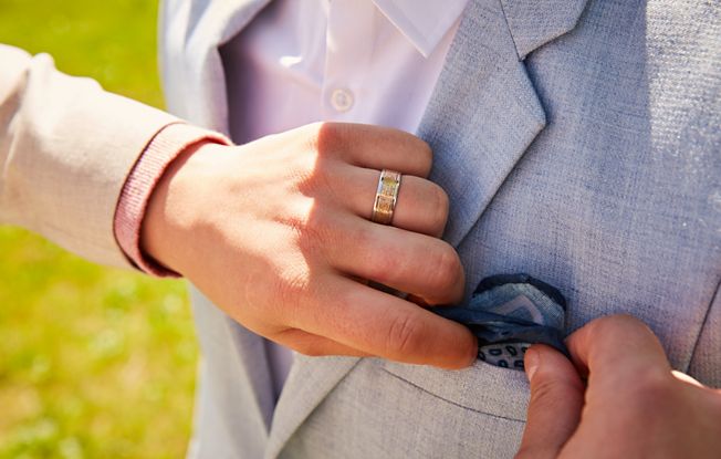 Close up of a man adjusting his partner's pocket square in his blazer 