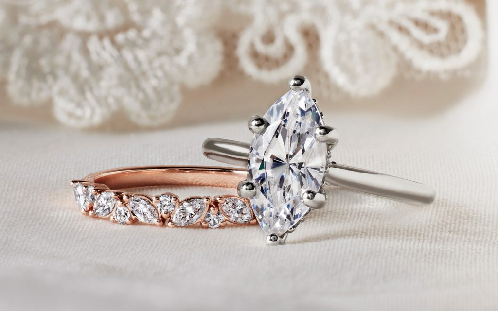 Marquise diamond engagement ring in white gold next to a rose gold ring. 