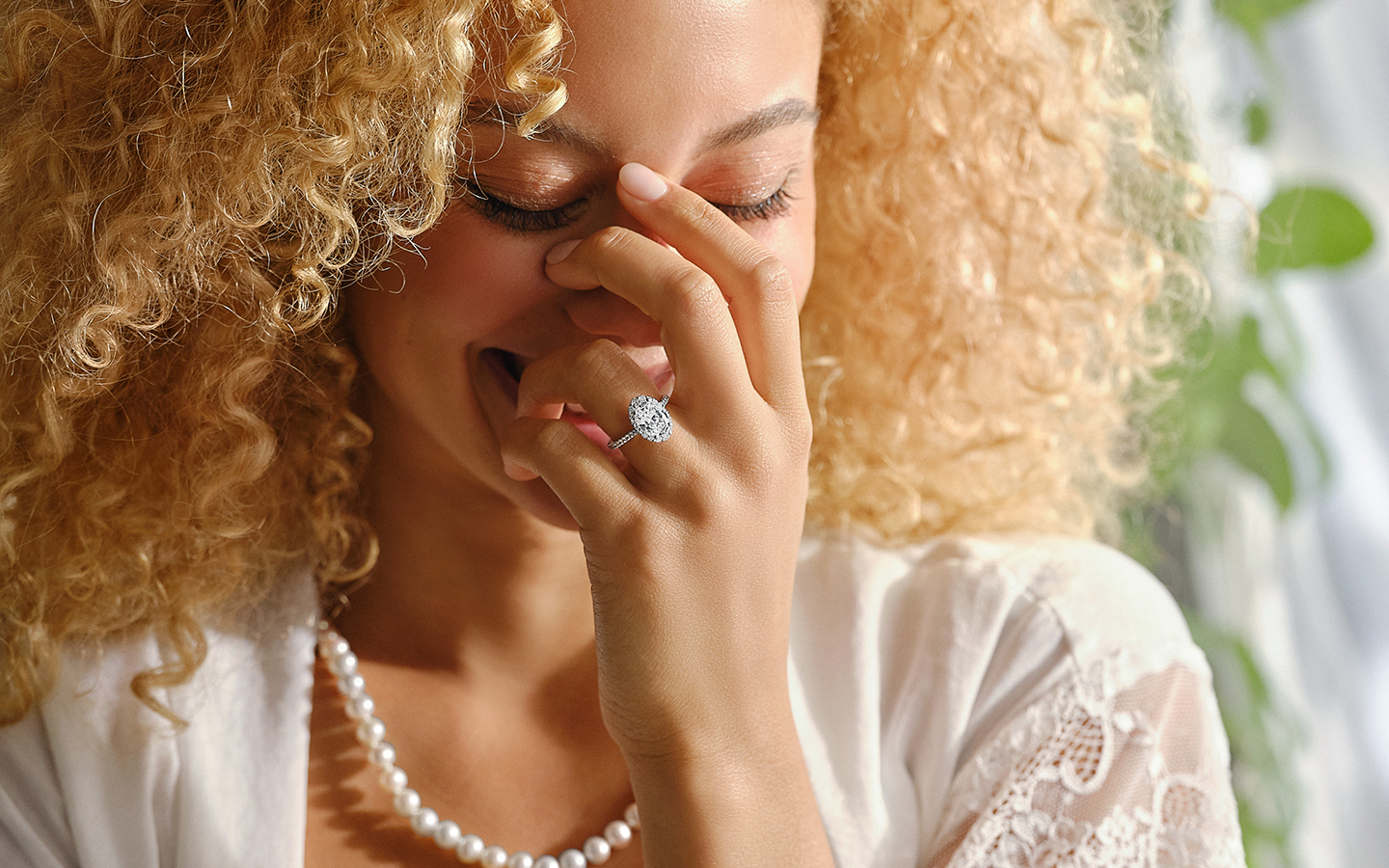 Bride smiling with her engagement ring on her hand, her hand is over her face. 