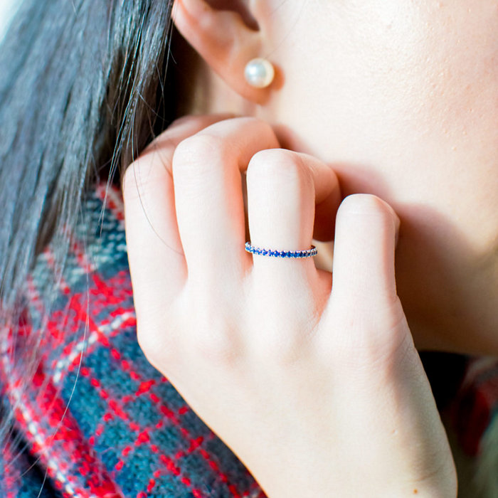 Close up of a woman's hand, she is wearing a sapphire eternity ring 