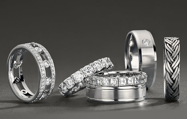 6 men's engagement rings in varying styles on a grey background