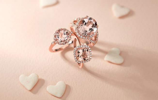 Three pink diamond rings with white diamond halos on a pink background with white hearts