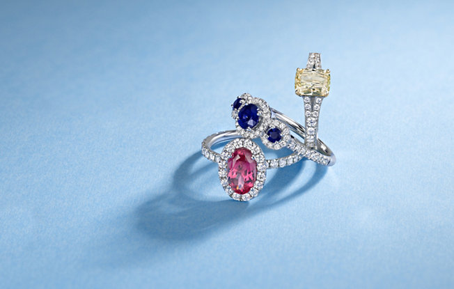 three gemstone engagement rings on a blue background