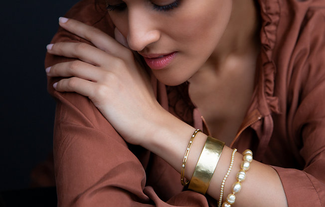 A woman modeling a stack of 4 gold bracelets