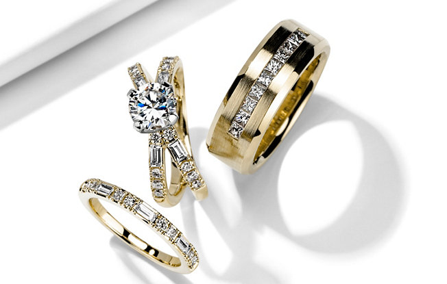 matching yellow gold diamond women’s engagement ring, women’s wedding ring and men’s wedding ring on a white background