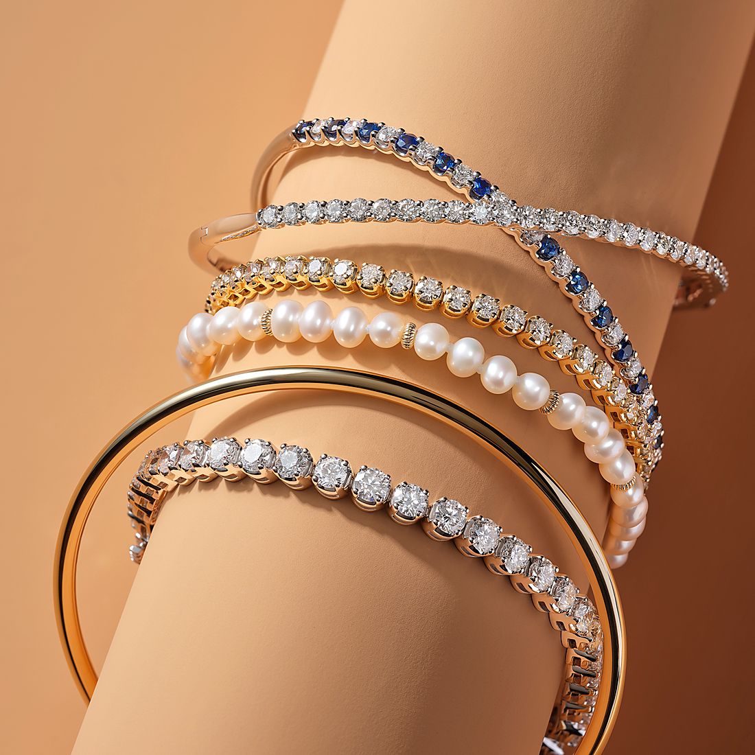 Six bracelets on a jewelry display including diamond, gemstone and gold bracelets 