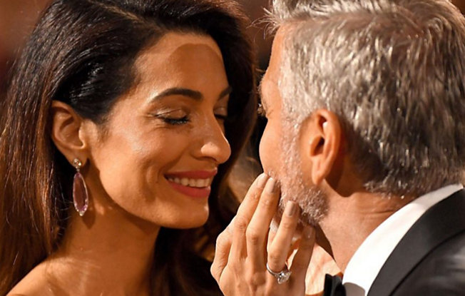 Amal and George Clooney embracing while looking into each other's eyes