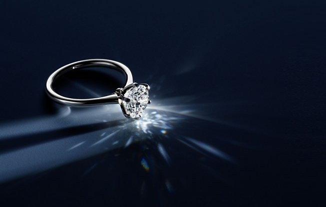 Round diamond 6 prong solitaire engagement ring on a blue background