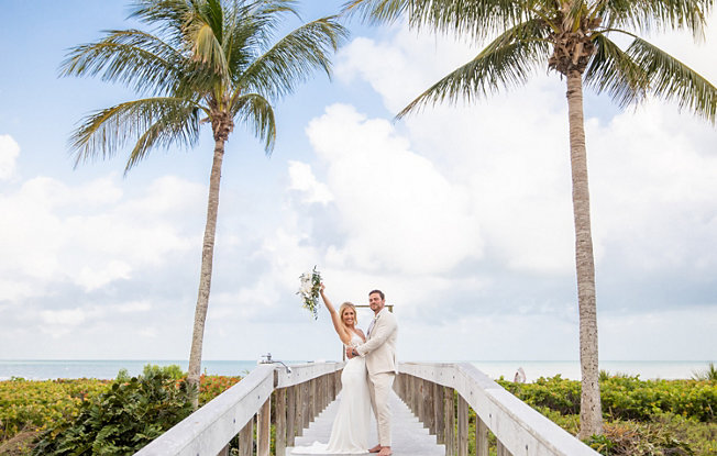 A bride and groom stand on the board walk at Sundial Beach Resort & Spa