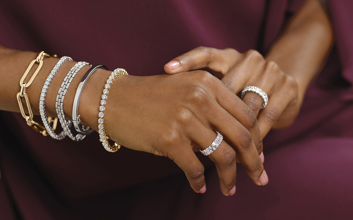 Photo of a woman’s hands, she is wearing gold and diamond bracelets.