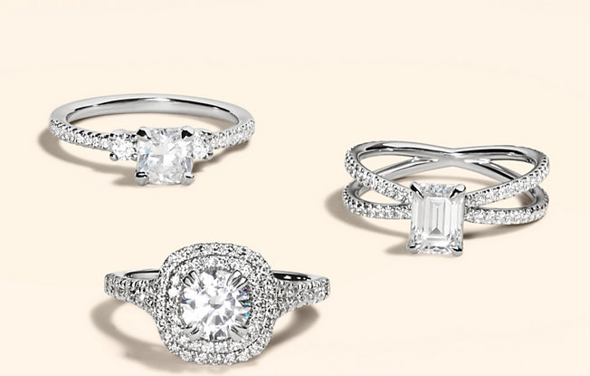 Three platinum and diamond engagement rings from Blue Nile on a yellow background