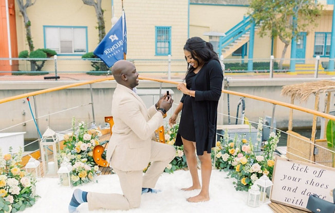 Man with a diamond engagement ring box proposing to a woman in a black dress