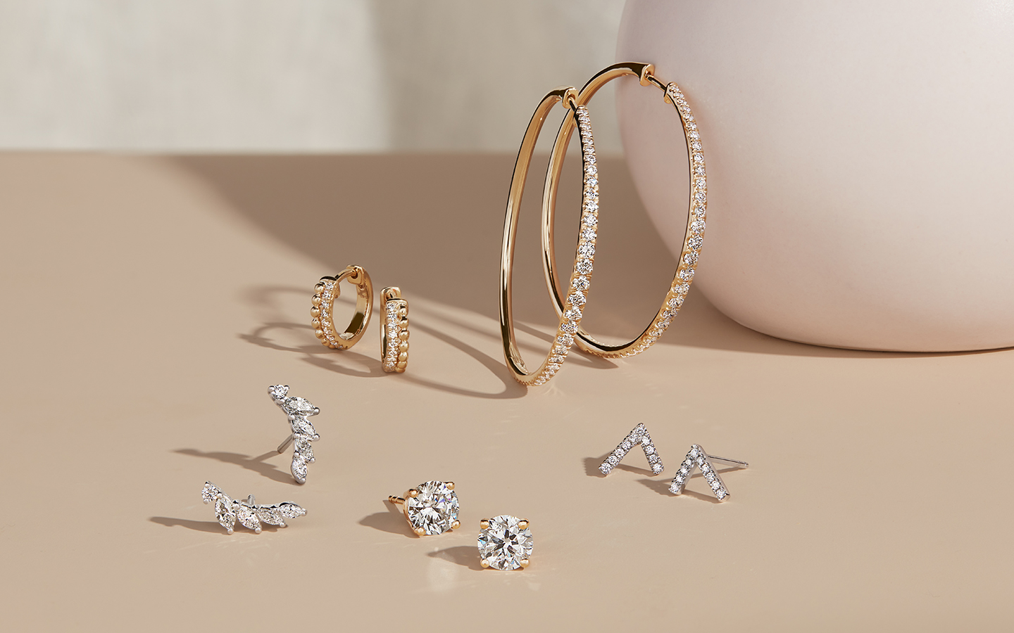 Five pairs of gold and diamond earrings including hoops and studs in yellow and white gold.