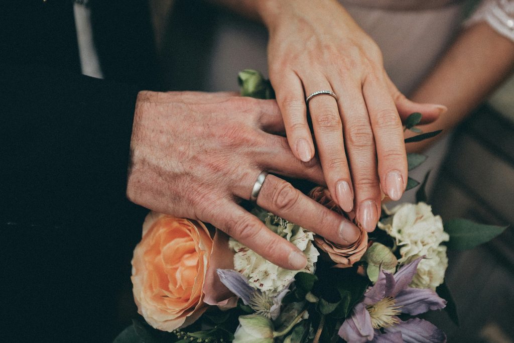 Photo of a couple’s hands on a commitment ceremony bouquet. 