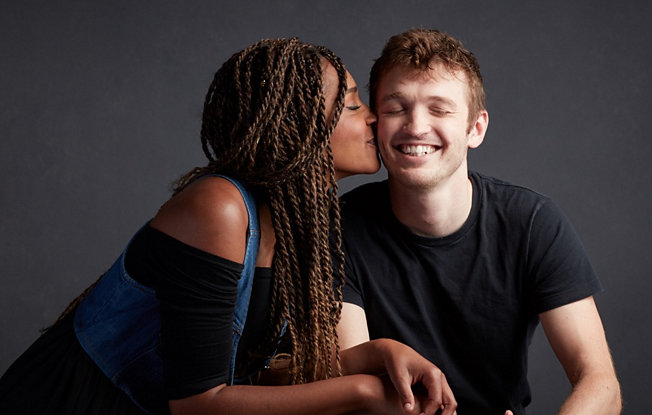 Woman kissing her smiling partner on the cheek.