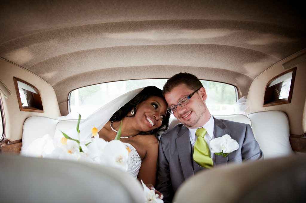 Bride and groom smiling in their car after their courthouse wedding.