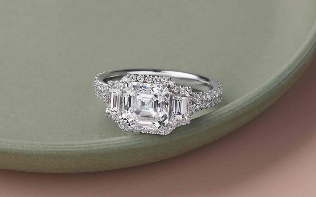 Three-stone engagement ring with center Asscher diamond in 14k white gold. 