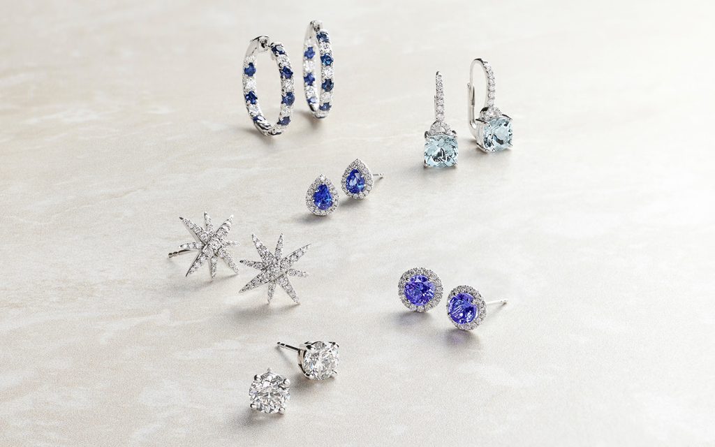 Pairs of sapphire, aquamarine, tourmaline and diamond earrings on a light background.