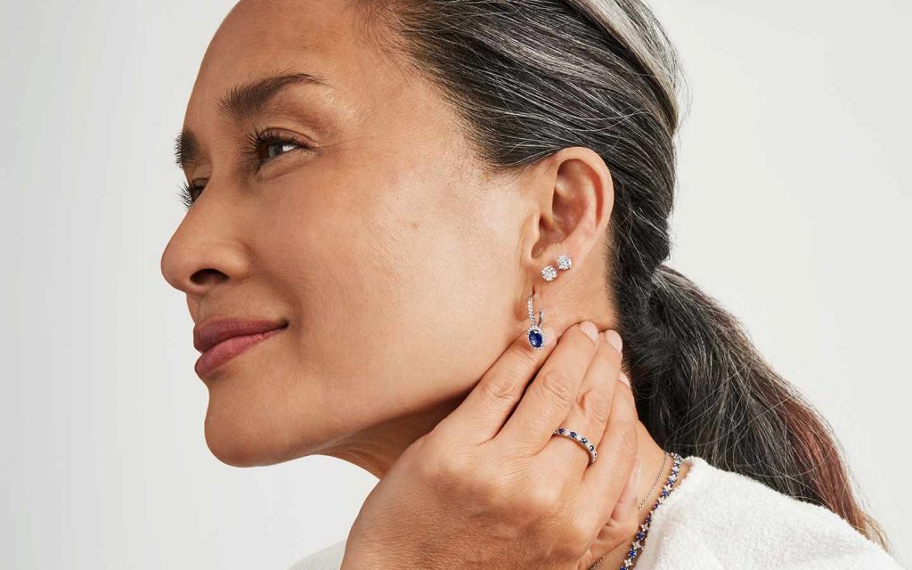 Close up of a smiling woman wearing three stacked earrings.