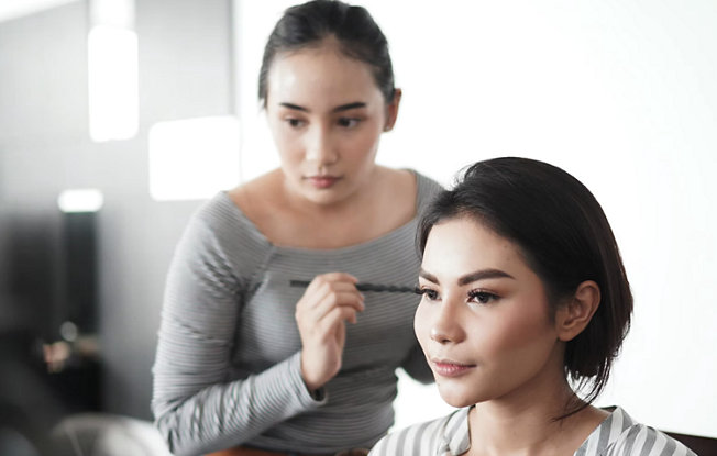A woman having her makeup done by a professional makeup artist