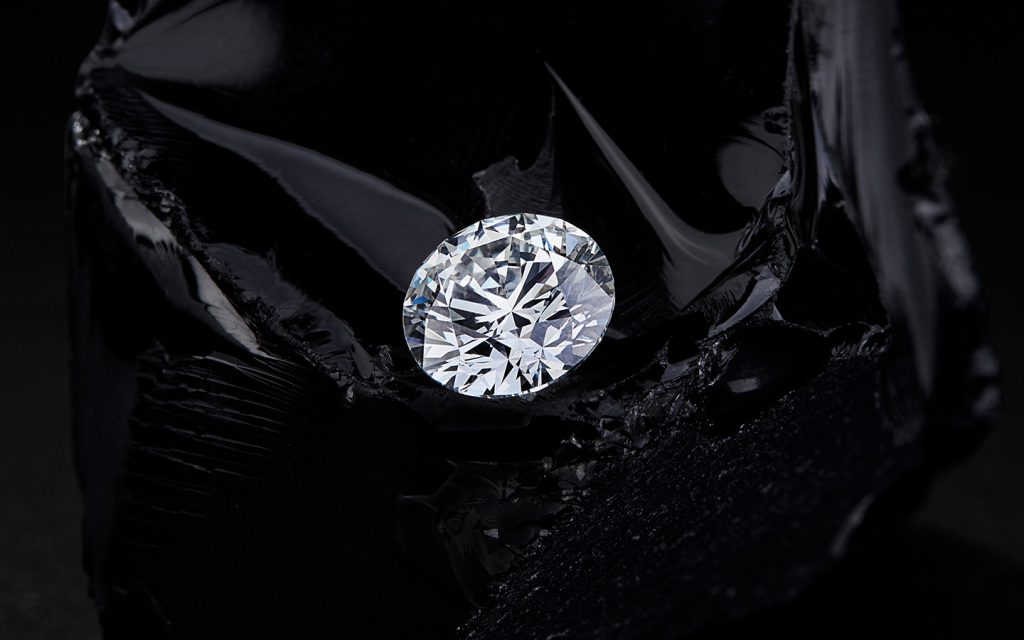 Round brilliant loose diamond on a dark background. 
