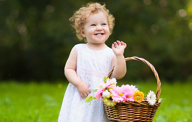 A little girl in a white dress holding a basket of flowers