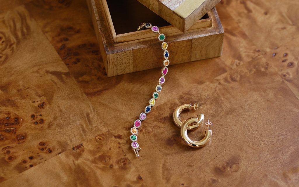 Photo of jewelry displayed on a dark table, including a multi-gemstone bracelet.
