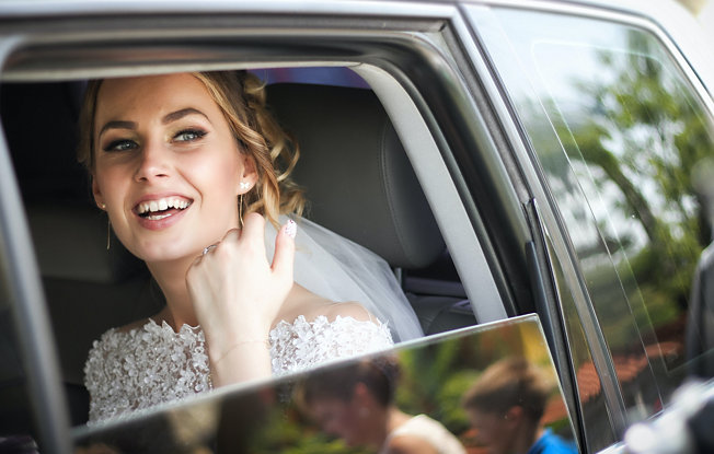 A bride looks out the window of a wedding car