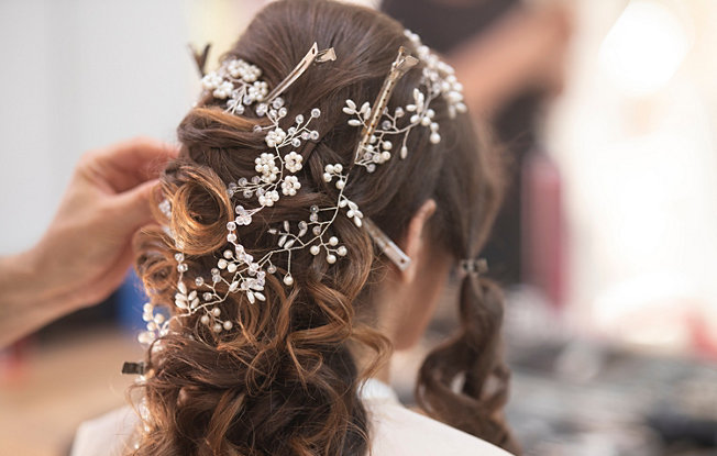 A woman with brown hair pulled back into a wedding updo with white flowers