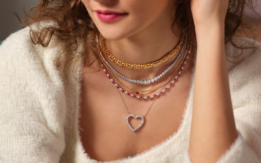 Photo of a woman’s necklace stack ,she is wearing a diamond heart necklace.
