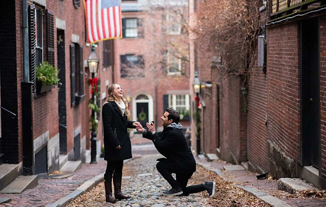 Man with diamond engagement ring on his knee proposing in a cobblestone street