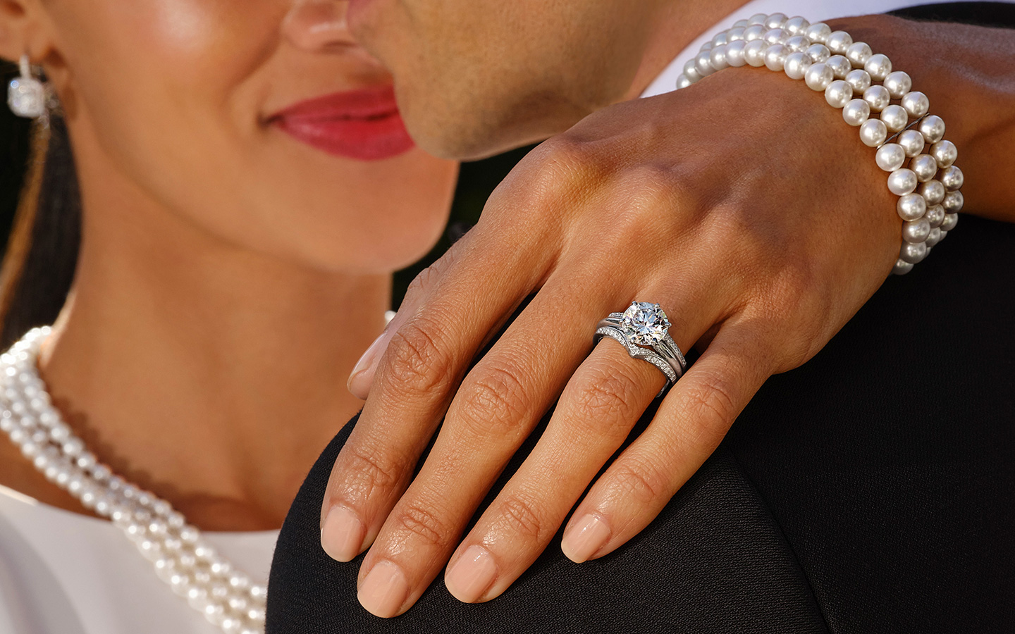 Close up of a bride and groom hugging on their wedding day, the bride’s diamond and platinum wedding ring set is the focal point.