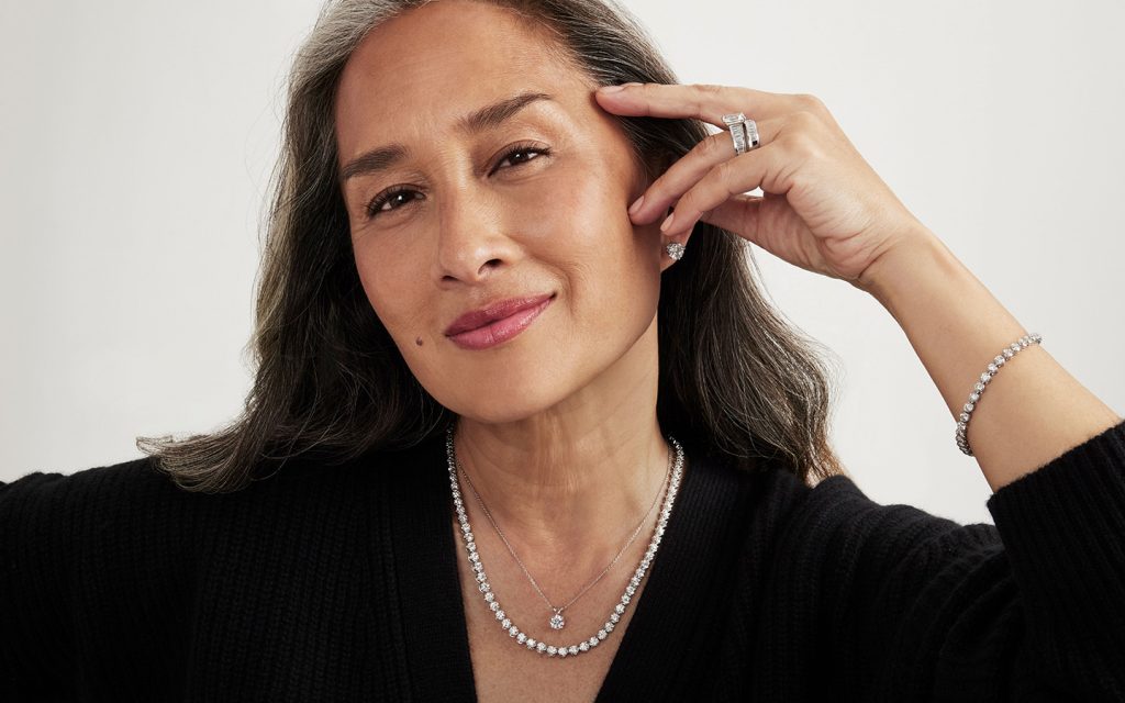 Woman smiling in lab grown diamond jewelry necklaces and a tennis bracelet.