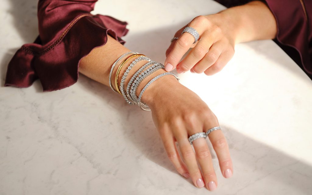 Photo of woman’s arms, she is wearing mixed metal jewelry. 