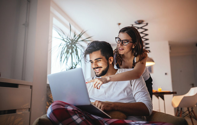Couple at home using a laptop to search for engagement rings