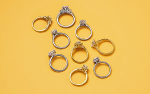 Gold and platinum engagement rings on a yellow background.