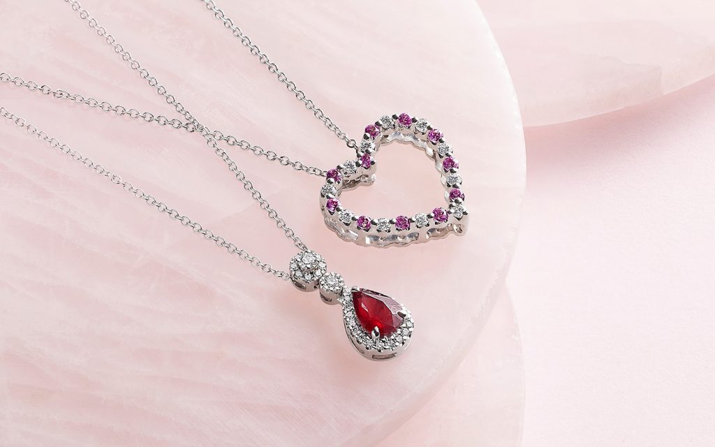 Pear ruby pendant next to a heart-shaped pendant with pink sapphires.