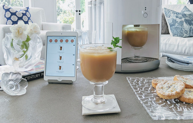 A living room with a phone, a drink and a somabar machine on a coffee table