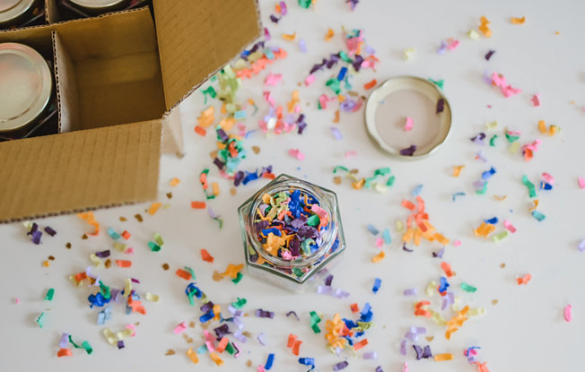 Colorful confetti in a mason jar and spread out over a white table