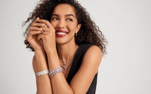 Woman smiling in Blue Nile bracelets and necklaces with diamonds and rubies.