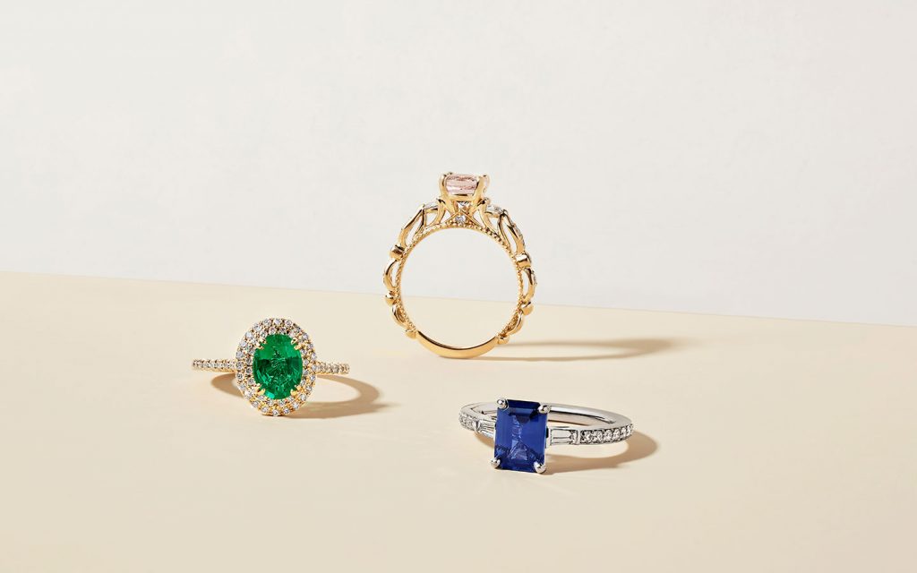 Three gemstone engagement rings with diamonds.